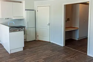 Lägenhet med mörkt trägolv, vitt kök samt vita väggar | Nivika Fastigheter AB (publ)