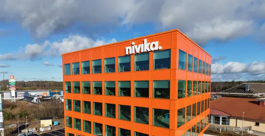 Kontorsfastighet med orange fasad och många fönster, nivikas logga längst upp | Nivika Fastigheter AB (publ)