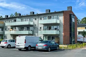 Flerbostadshus med vit fasad samt röd tegelfasad, frostade glasbalkonger | Nivika Fastigheter AB (publ)