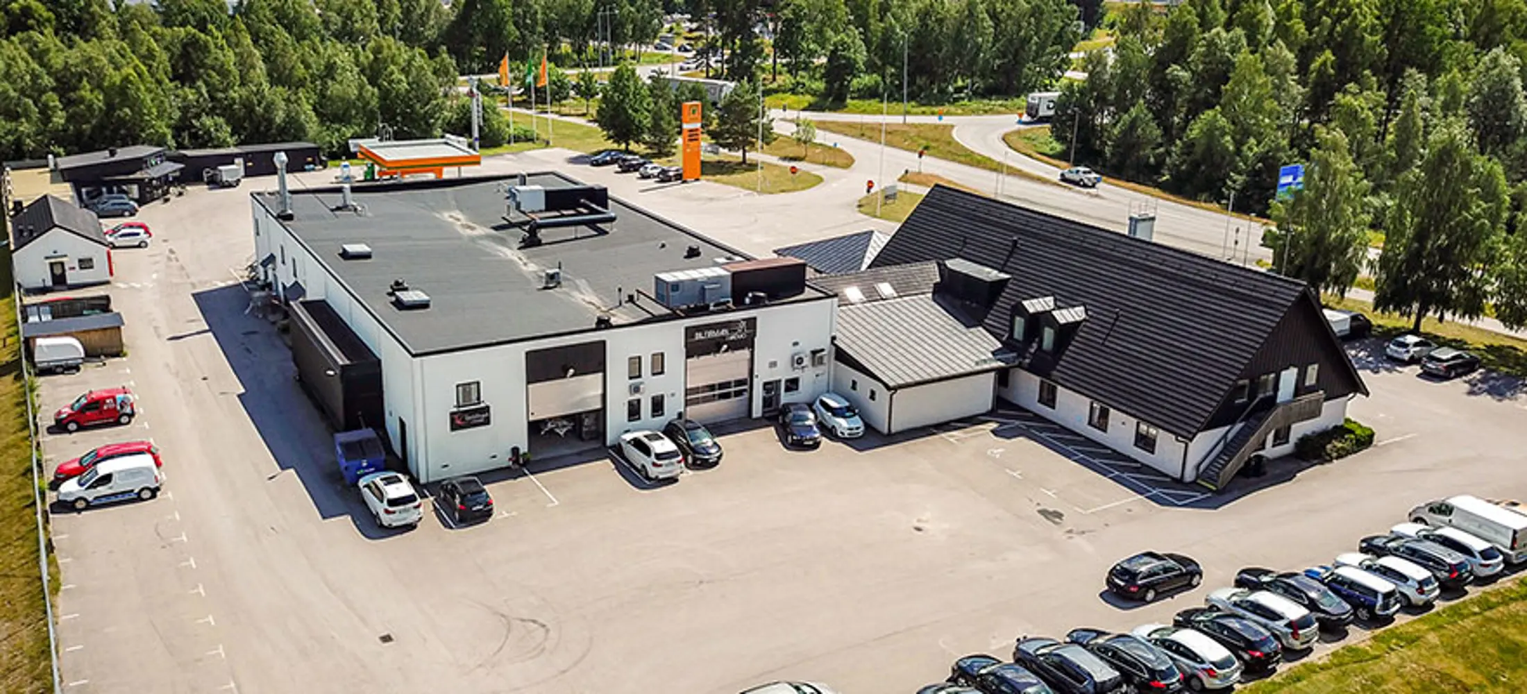 Industrifastighet med vit fasad och svart plåttak, med tillhörande parkering | Nivika Fastigheter AB (publ)