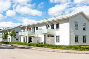 Flerbostadshus med vit träfasad, vita fönster och frostad balkong | Nivika Fastigheter AB (publ)