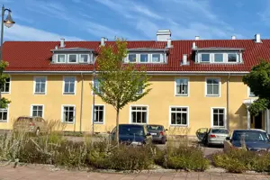 Flerbostadsfastighet med gul fasad och rött tegeltak, vita fönster | Nivika Fastigheter AB (publ)