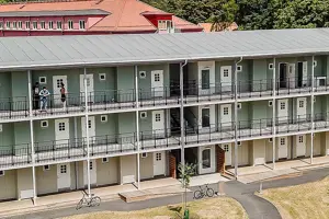 Flerbostadshus med mintgrön fasad, vita fönster och dörrar, balkong längs hela framsidan | Nivika Fastigheter AB (publ)