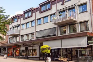 Flerbostadshus med grå och röd tegelfasad, vita och svarta fönster, kommersiella fastigheter på första våningen | Nivika Fastigheter AB (publ)