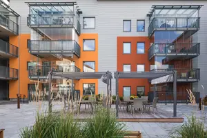 Flerbostadshus med färgglad fasad, svarta fönster och balkonger | Nivika Fastigheter AB (publ)