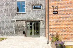 Flerbostadsfastighet med grå och orange tegelfasad, närbild på en entré