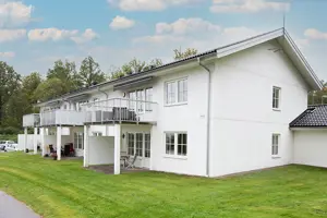 Flerbostadsfastighet med vit fasad samt fönster, terrass på våning 1 och balkong på våning 2 | Nivika Fastigheter AB (publ)