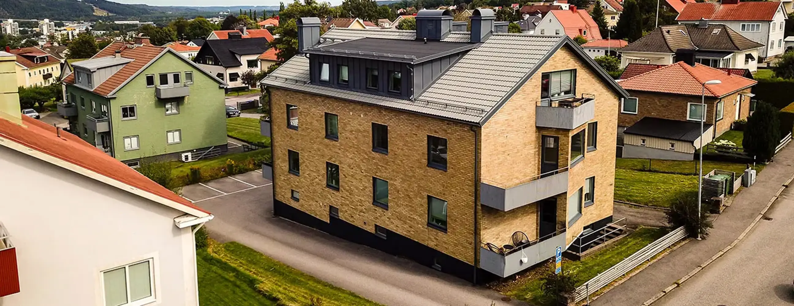 Flerbostadshus med tegelfasad, svarta fönster och dörrar samt svart tegeltak | Nivika Fastigheter AB (publ)