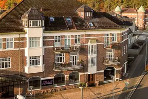 Flerbostadsfastighet med röd tegelfasad, vita fönster och rött tegeltak | Nivika Fastigheter AB (publ)