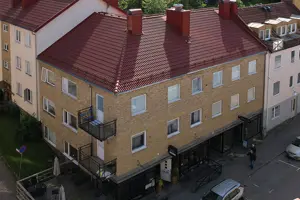 Flerbostadshus med vit och gul fasad, rött tegeltak | Nivika Fastigheter AB (publ)