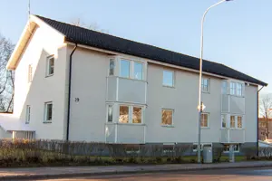 Vitt flerbostadshus med svart tak, vita fönster | Nivika Fastigheter AB (publ)