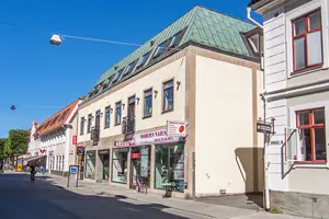 Flerbostadshus med beige putsad fasad och grönt koppartak | Nivika Fastigheter AB (publ)