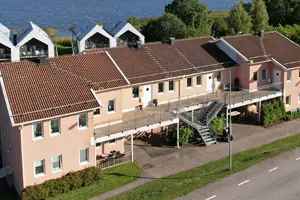 Flerbostadsfastighet med persikofärgad fasad och rött tegeltak, vita fönster | Nivika Fastigheter AB (publ)