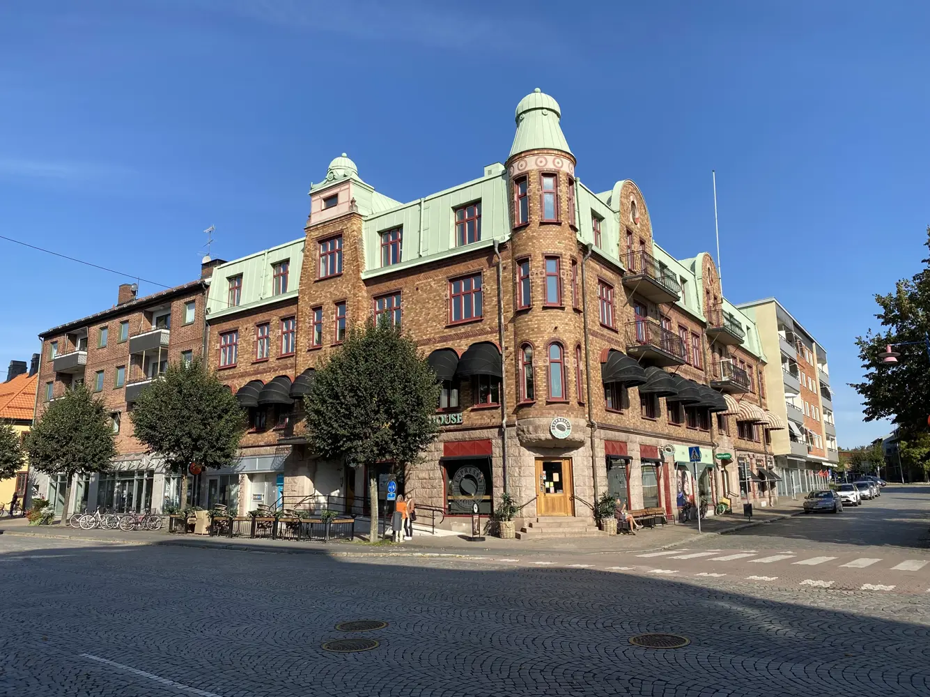 Flerbostadshus med sten och tegelfasad, röda fönster och koppartak | Nivika Fastigheter AB (publ)