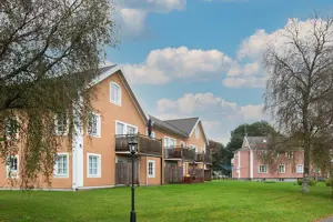 Flerbostadshus med orange putsad fasad, vita fönster och knutar | Nivika Fastigheter AB (publ)