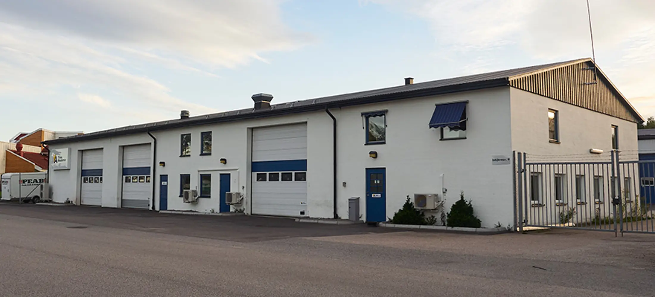 Industrifastighet med vit fasad och blå dörrar, vitblå portar | Nivika Fastigheter AB (publ)