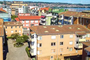 Flerbostadshus med gul tegelfasad och rött tegeltak, nära Vättern | Nivika Fastigheter AB (publ)